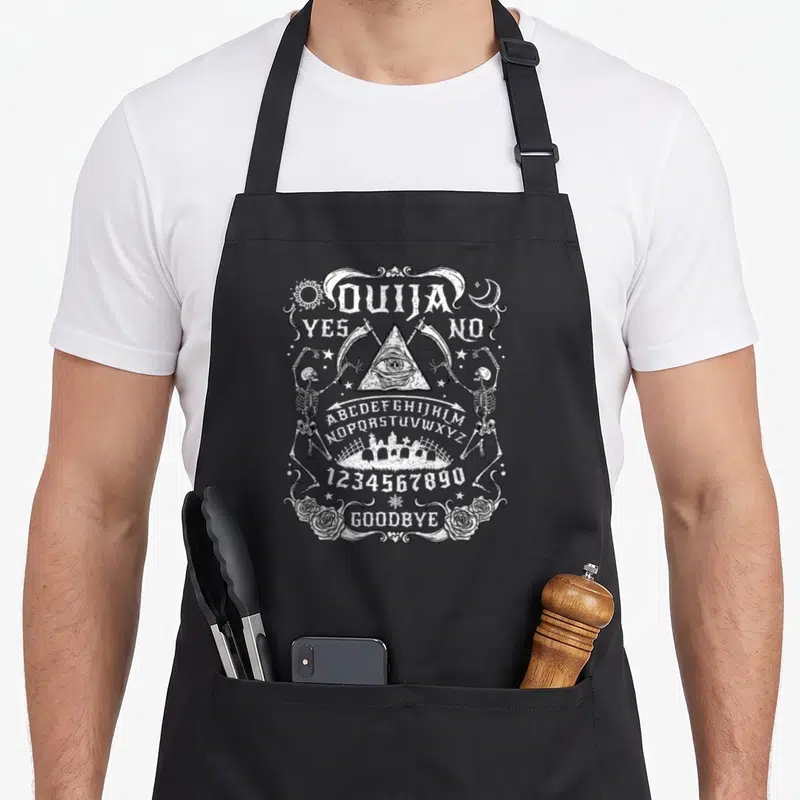 Tablier de cuisine noir avec illustration blanche planche Ouija, squelettes, roses et œil mystique.