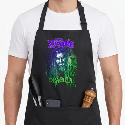 Tablier de cuisine noir avec illustration colorée de Rob Zombie et le texte Dragula en bas.