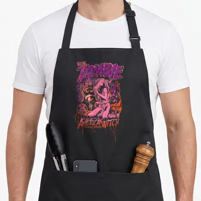 Tablier de cuisine noir avec illustration sorcière pastel rose et violet, symboles occultes et texte Rob Zombie American Witch.