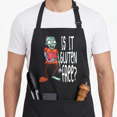 Tablier de cuisine noir avec un zombie aux intestins roses et le texte Is it gluten free en blanc.