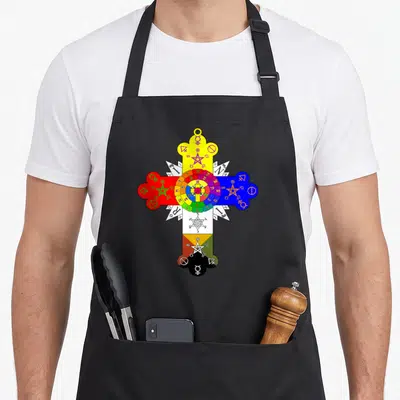 Tablier de cuisine noir avec une grande croix colorée comportant des symboles alchimiques et des pentagrammes sur fond uni.