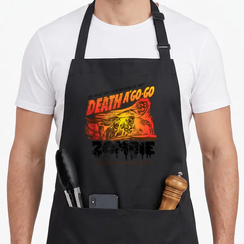 Tablier de cuisine noir avec illustration orange d'un crash mortel et le mot Zombie en lettres dégoulinantes.