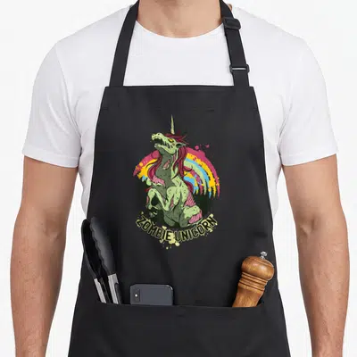 Tablier de cuisine noir avec illustration d'un zombie licorne vert et rose sur fond arc-en-ciel.