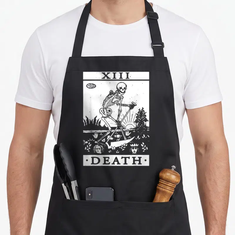 Tablier de cuisine noir avec illustration blanche carte tarot Death XIII squelette et faucille style gravure ancienne.