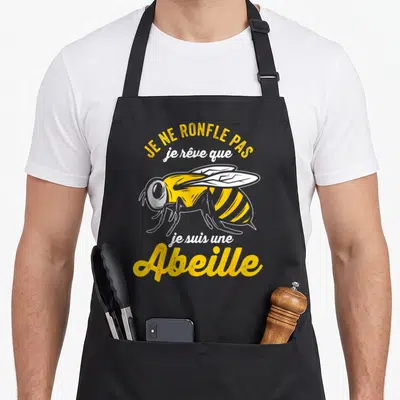Tablier de cuisine noir avec une illustration d'abeille jaune et le texte Je ne ronfle pas je rêve que je suis une Abeille.