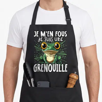 Tablier de cuisine noir avec une grenouille verte aux grands yeux jaunes et le texte Je m'en fous je suis une grenouille en blanc.