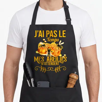 Tablier de cuisine noir avec inscription jaune J'ai pas le temps mes abeilles m'attendent et trois insectes sur un nid d'abeille.
