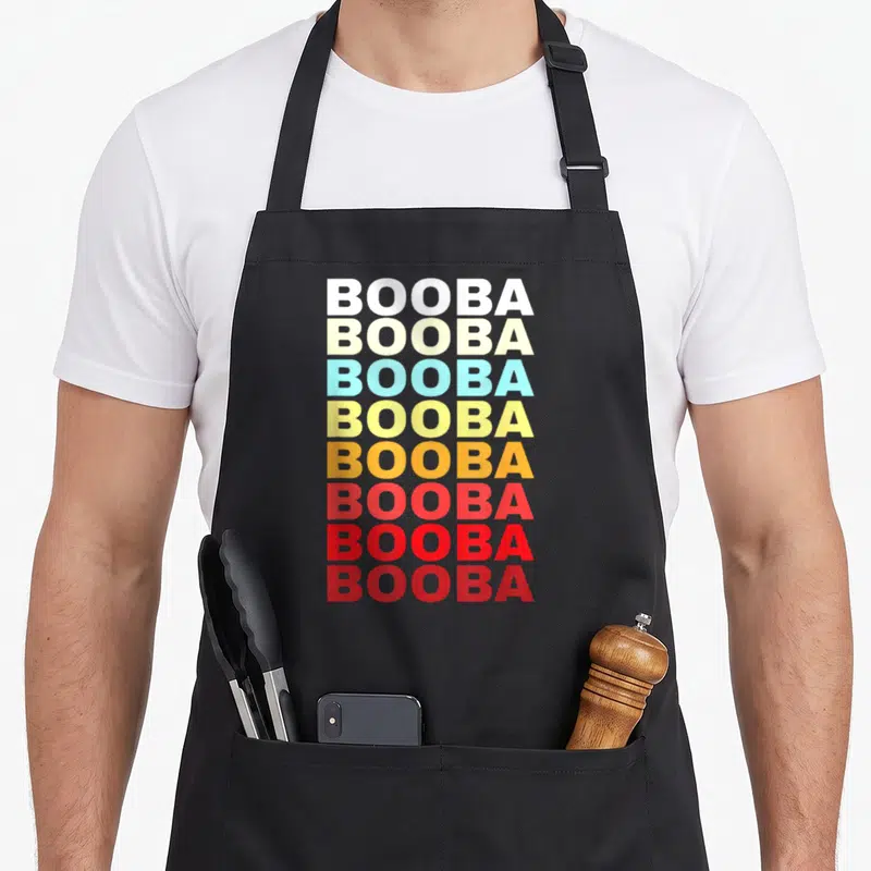 Tablier de cuisine noir avec le nom Booba répété verticalement en lettres blanches, jaunes, oranges et rouges.