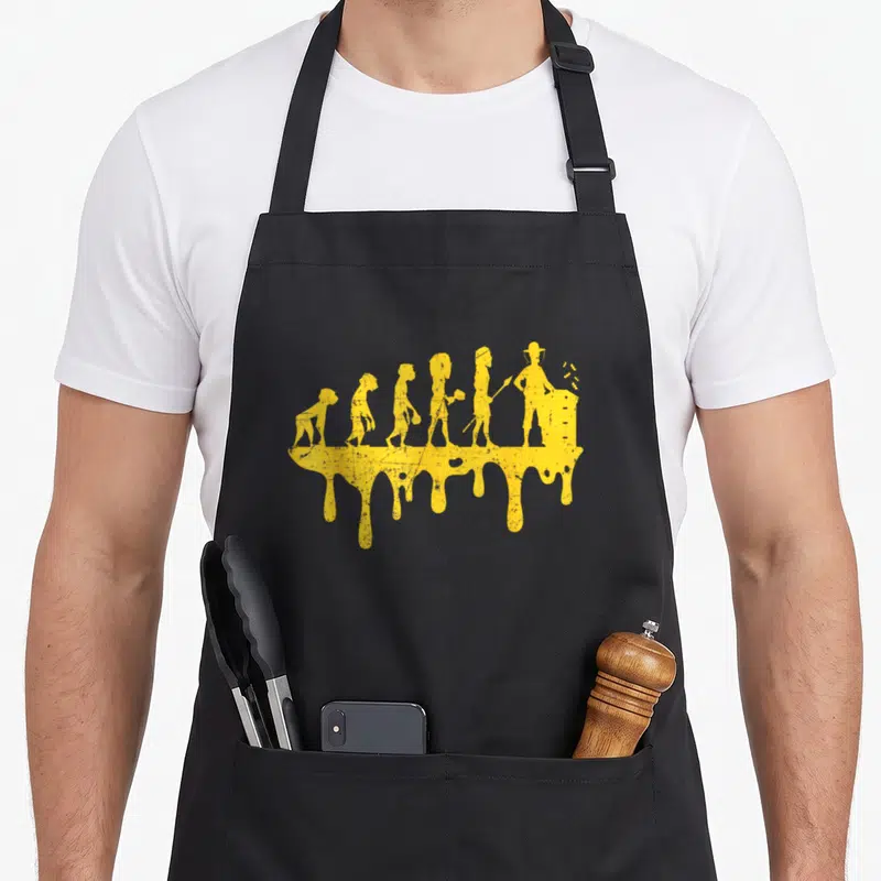 Tablier de cuisine noir avec illustration jaune représentant l'évolution de l'apiculteur sur une flaque de miel coulant.