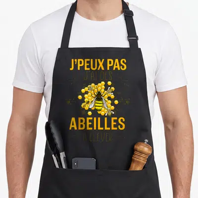Tablier de cuisine noir avec inscription J'peux pas j'ai des abeilles à élever et illustration d'abeille sur ruche.