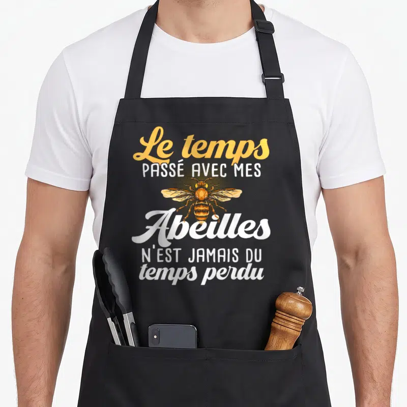 Tablier de cuisine noir avec une illustration d'abeille orange et le texte Le temps passé avec mes Abeilles n'est jamais du temps perdu.