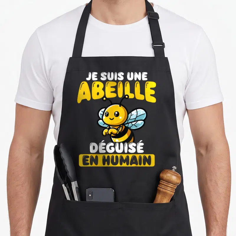 Tablier de cuisine noir avec une abeille jaune souriante et le texte Je Suis Une Abeille Déguisé En Humain imprimé en lettres jaunes et blanches.