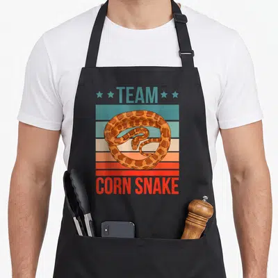 Tablier de cuisine noir avec illustration rétro d'un serpent corn snake sur fond de bandes colorées et texte Team Corn Snake.