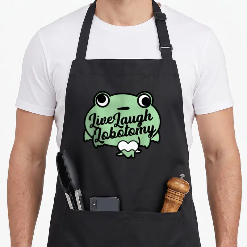Tablier de cuisine noir avec illustration d'une grenouille verte aux yeux exorbités et texte noir Live Laugh Lobotomy sur le ventre.
