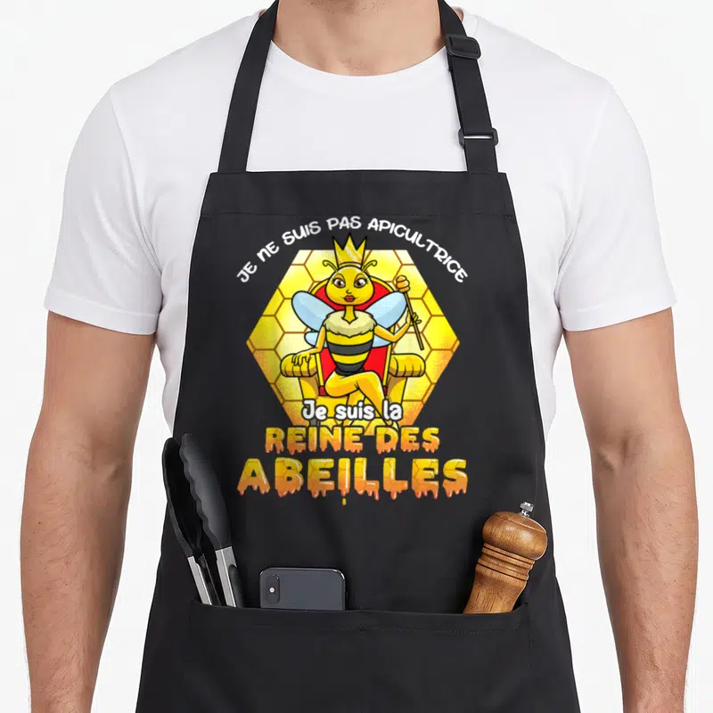 Tablier de cuisine noir avec une reine des abeilles assise sur un trône doré.