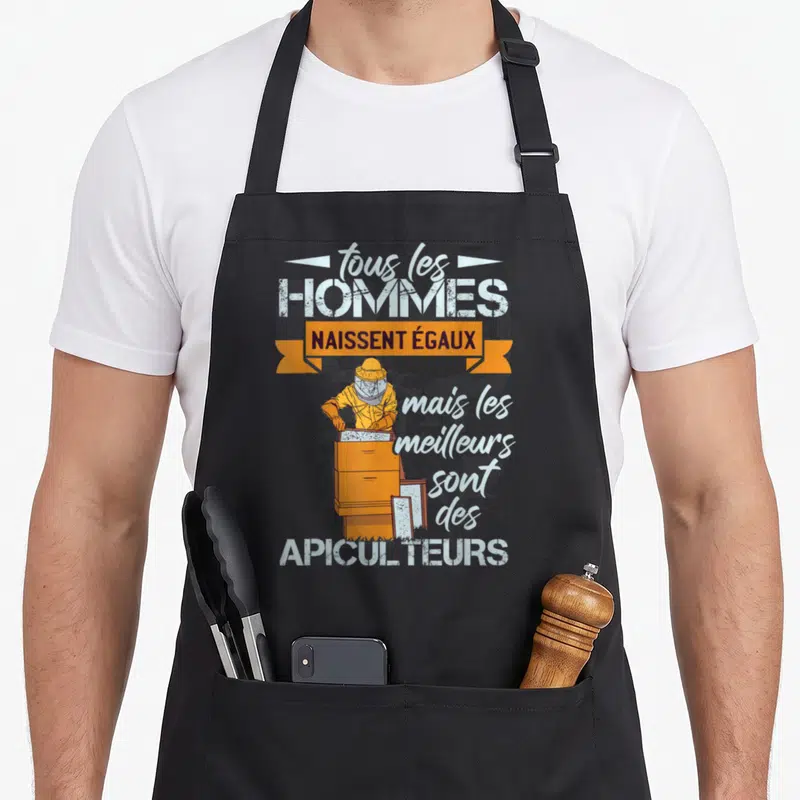 Tablier de cuisine noir avec illustration d'un apiculteur en tenue jaune manipulant une ruche orange et un message humoristique.
