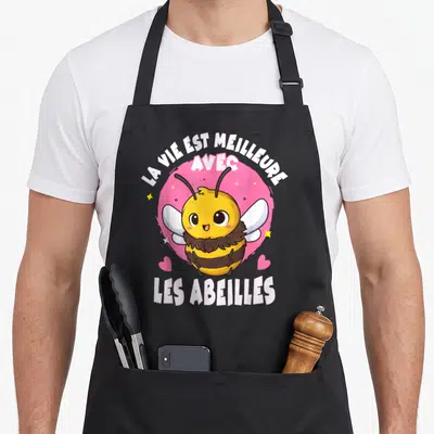 Tablier de cuisine noir avec une abeille jaune souriante, des cœurs roses et le texte La vie est meilleure avec les abeilles.