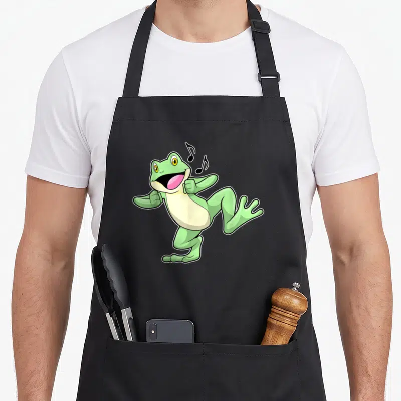 Tablier de cuisine noir avec illustration d'une grenouille verte dansante aux notes de musique noires flottant près de sa bouche ouverte.