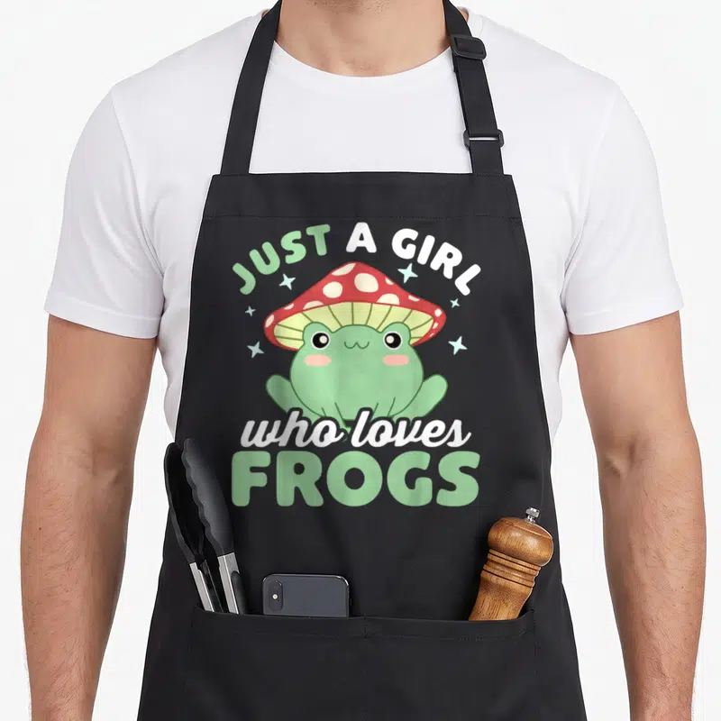Tablier de cuisine noir avec une grenouille verte au chapeau champignon rouge et texte Just a Girl Who Loves Frogs.