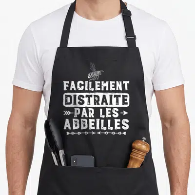 Tablier de cuisine noir avec inscription blanche facilement distraite par les abeilles et un dessin d'insecte au-dessus du texte.
