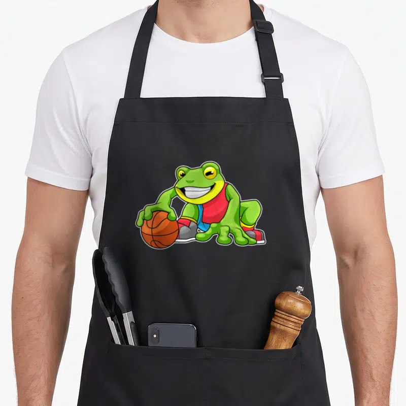 Tablier de cuisine noir avec une grenouille basketteur en maillot rouge tenant un ballon orange.