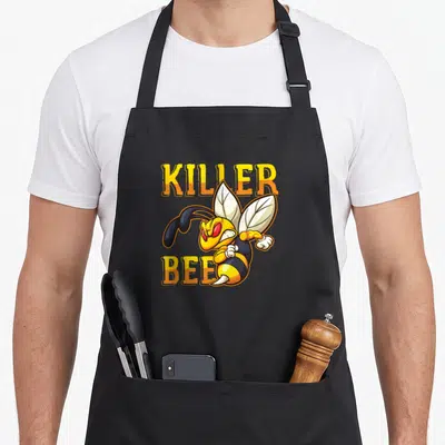 Tablier de cuisine noir avec illustration colorée d'une guêpe cartoon aux yeux rouges et texte Killer Bee en orange.