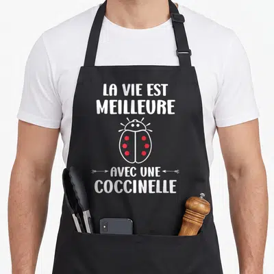 Tablier de cuisine noir avec une illustration de coccinelle rouge et le texte La vie est meilleure avec une coccinelle en blanc.