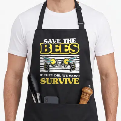 Tablier de cuisine noir avec deux abeilles stylisées et le texte Save The Bees en typographie jaune et blanche.