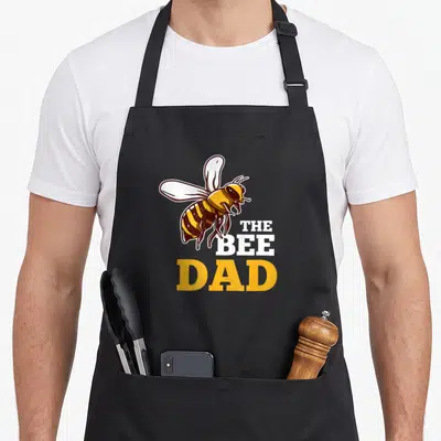 Tablier de cuisine noir avec illustration d'abeille et texte The Bee Dad en blanc et jaune.
