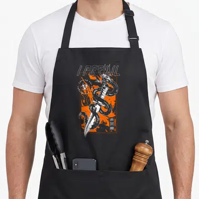 Tablier de cuisine noir avec un serpent enroulé autour d'un couteau et le texte I Prevail sur fond orange.