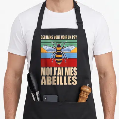 Tablier de cuisine noir avec illustration d'abeille sur bandes colorées et texte humoristique beige