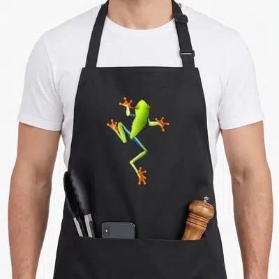 Tablier de cuisine noir avec une grenouille verte aux pattes orange et bleues en position dynamique.