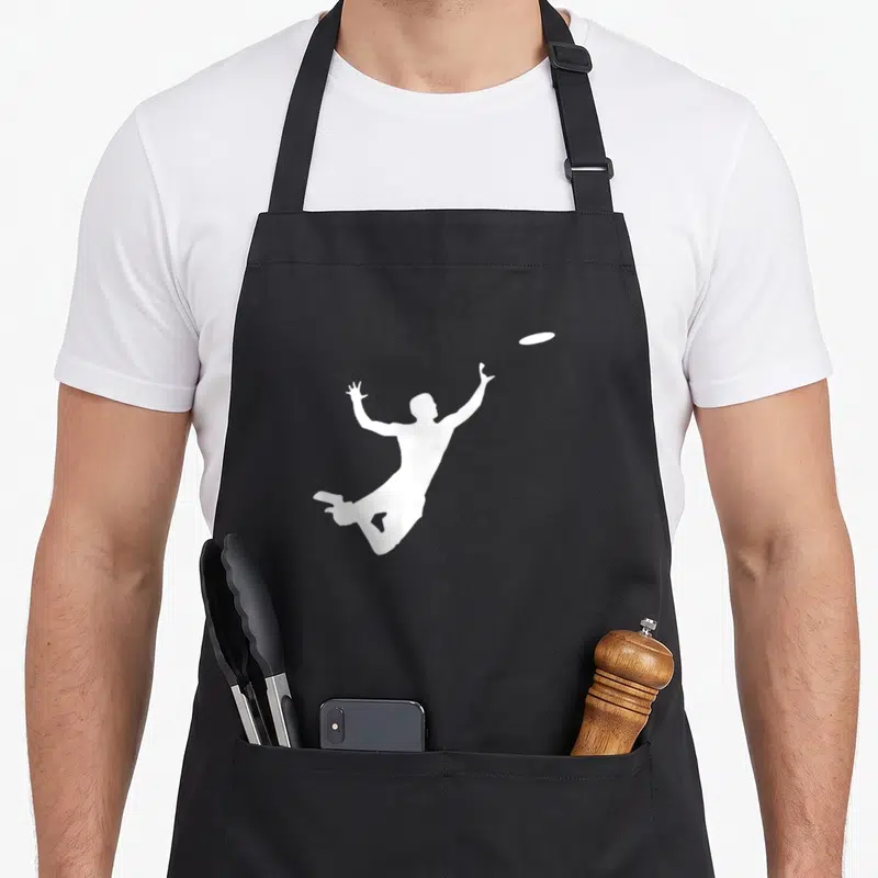 Tablier de cuisine noir avec silhouette blanche d'un homme sautant pour attraper un frisbee.