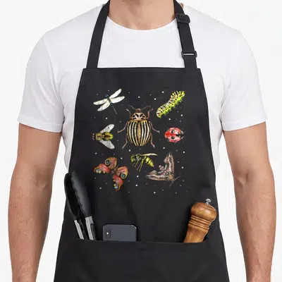 Tablier de cuisine noir avec illustration colorée de scarabée, coccinelle, libellule et autres insectes sur fond gris uni.
