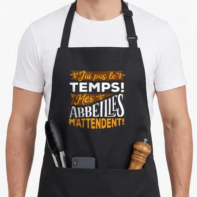 Tablier de cuisine noir avec l'inscription J'ai pas le temps Mes abeilles m'attendent entourée d'illustrations d'insectes ailés.