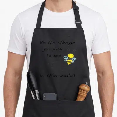 Tablier de cuisine noir avec inscription Be the Change You Wish to See In This World et bee jaune aux ailes bleues.