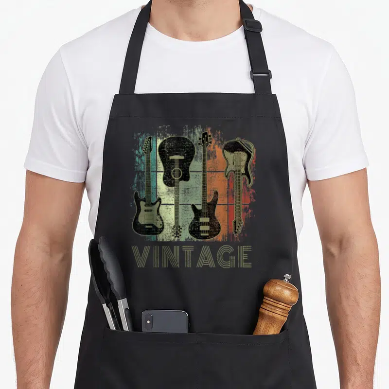 Tablier de cuisine noir avec illustration de quatre guitares vintage sur fond coloré et le mot vintage en bas.