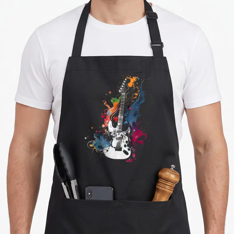Tablier de cuisine noir avec illustration d'une guitare électrique blanche entourée de couleurs vives et d'éclaboussures artistiques.