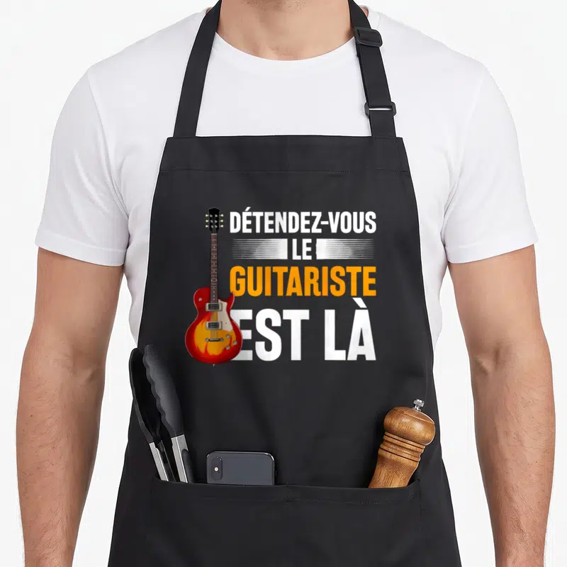 Tablier de cuisine noir avec illustration de guitare électrique rouge et texte blanc orange Détendez-vous le guitariste est là
