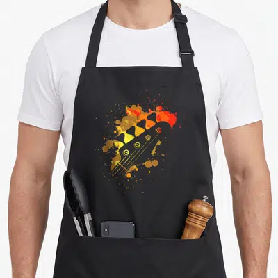 Tablier de cuisine noir avec illustration colorée d'une tête de guitare basse aux éclats orange et jaune.