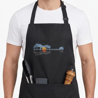 Tablier de cuisine noir avec illustration d'une guitare formée par un paysage de coucher de soleil et d'arbres bleus.