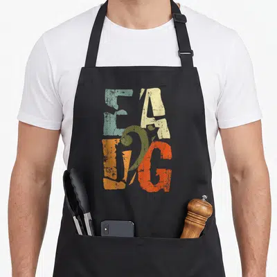 Tablier de cuisine noir avec les lettres EADG colorées et une clé de basse verte imprimée sur le devant.