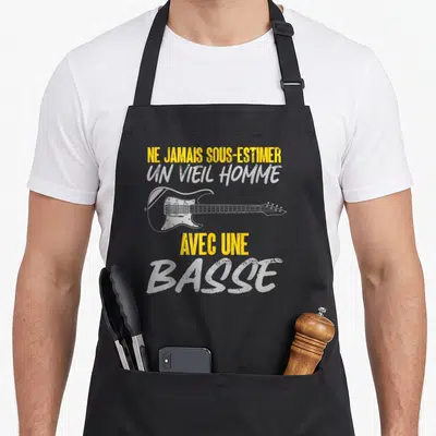 Tablier de cuisine noir avec illustration de basse électrique et texte jaune et blanc sur fond uni