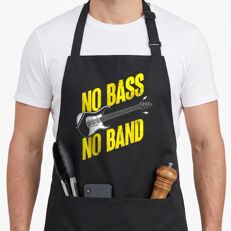 Tablier de cuisine noir avec inscription jaune No Bass No Band et dessin de guitare basse blanche.