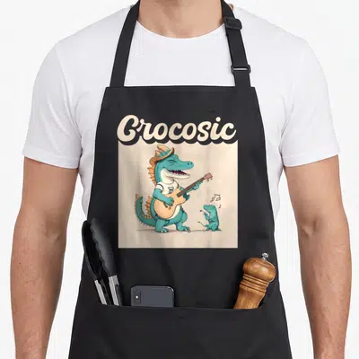 Tablier de cuisine noir avec un crocodile turquoise jouant de la guitare sous le mot Crocosic