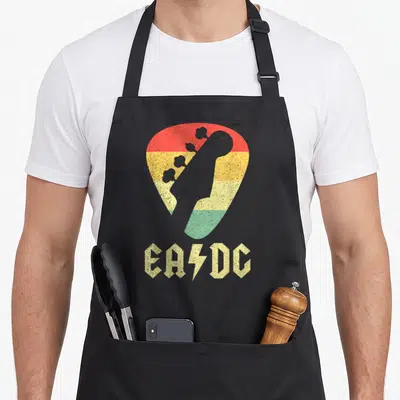 Tablier de cuisine noir avec motif plectre aux couleurs reggae et texte EADG stylisé en jaune.