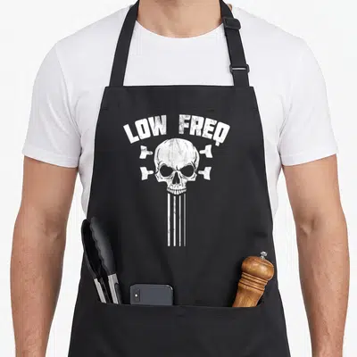 Tablier de cuisine noir avec un crâne blanc, des cordes et le texte Low Freq imprimé au centre.