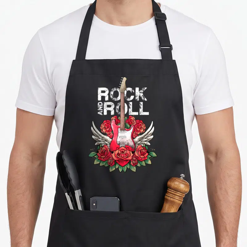 Tablier de cuisine noir avec une guitare électrique rouge, des ailes blanches et un bouquet de roses rouges entourant le texte Rock and Roll.