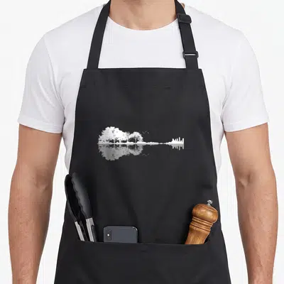 Tablier de cuisine noir avec illustration blanche d'arbres et de ville se reflétant dans l'eau.