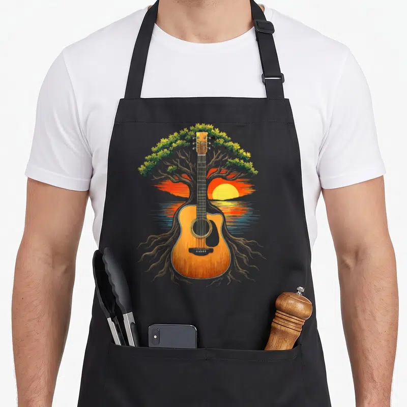 Tablier de cuisine noir avec illustration d'un arbre dont le tronc forme une guitare acoustique orange devant un soleil couchant.